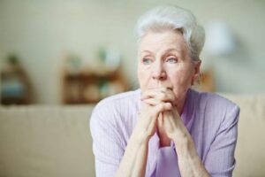 Elderly woman keeping hands by her lips Elderly woman keeping hands by her lips