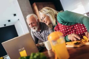 Happy retired couple browsing the internet together on a laptop computer.Quarantine. Health concept. Moulton Webinars
